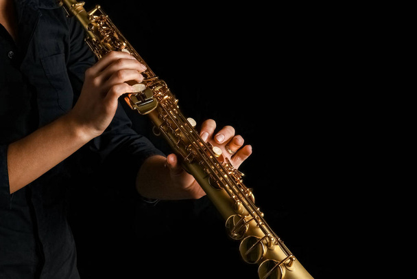 soprano saxophone in hands on a black background - Фото, зображення