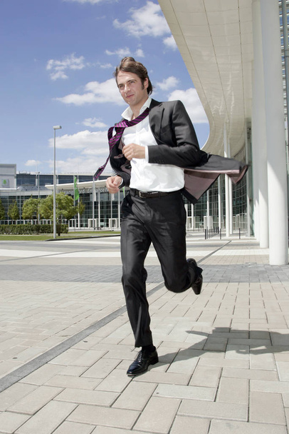jeune homme d'affaires en costume avec mallette marchant dans la rue - Photo, image