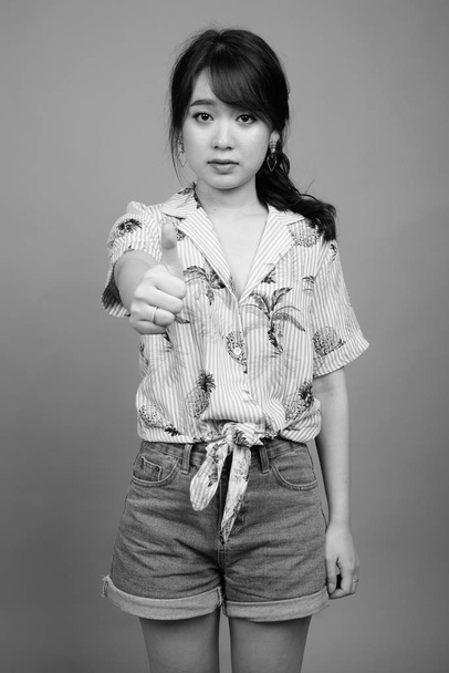 Studio colpo di giovane bella asiatica donna turistica pronta per le vacanze contro sfondo grigio in bianco e nero - Foto, immagini