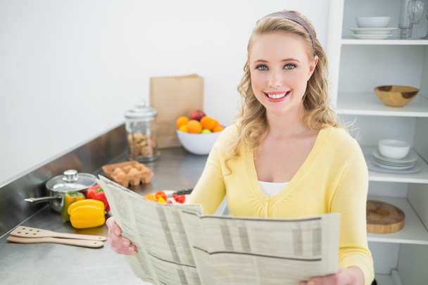 Smiling cute blonde holding newspaper - Photo, image