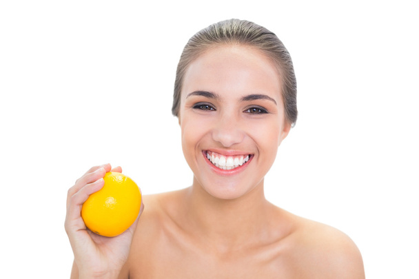 Happy young woman holding an orange - Zdjęcie, obraz