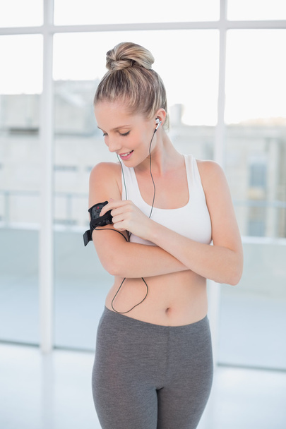 Smiling sporty blonde changing music on her mp3 player - 写真・画像