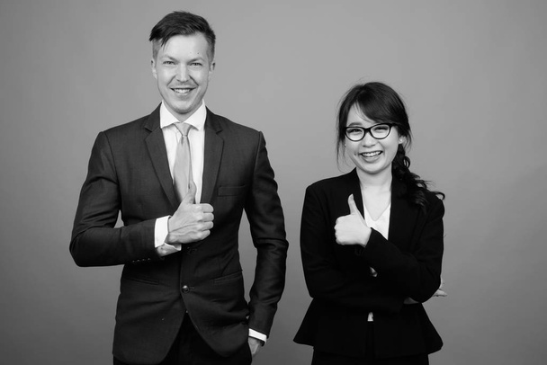 Studio colpo di giovane multi etnico business coppia di lavoro insieme contro sfondo grigio in bianco e nero - Foto, immagini