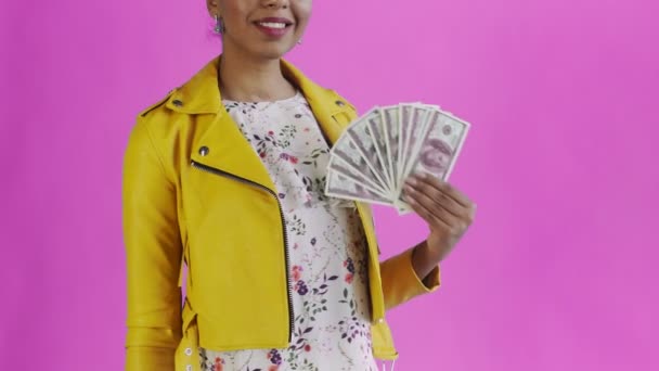 Portrait of african american woman with money fan on pink Background in Studio. Yellow jacket - Filmati, video