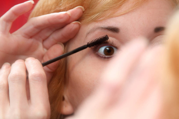 close up of woman applying mascara on her eyelashes - Zdjęcie, obraz