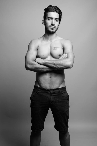 Young handsome Persian man shirtless against gray background - Foto, Imagem