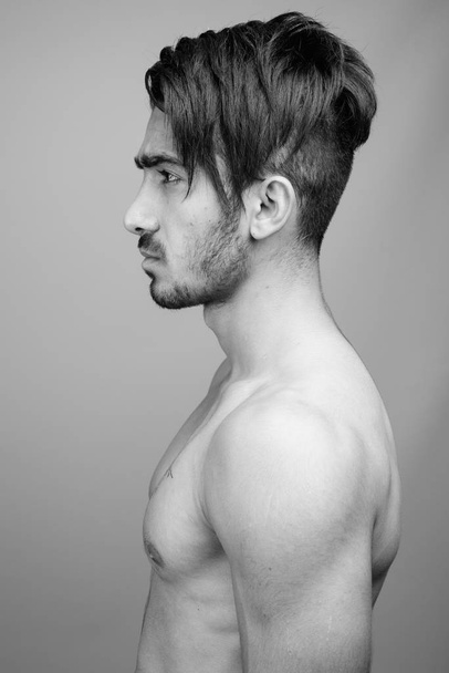 Young handsome Persian man shirtless against gray background - Photo, Image