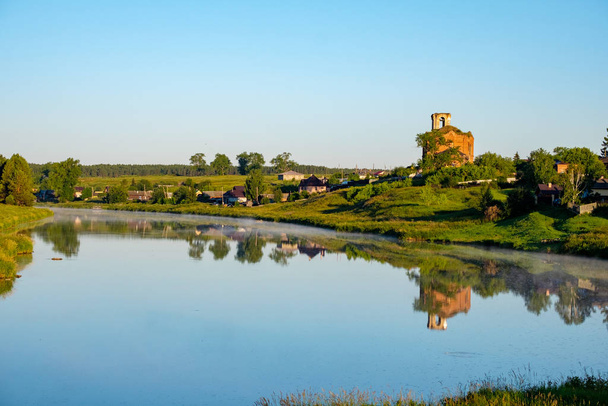 中央ロシア川の田園風景と銀行の老朽化した教会 - 写真・画像