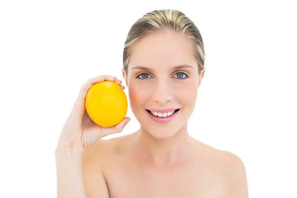 Sonriente mujer rubia fresca sosteniendo una naranja
 - Foto, Imagen
