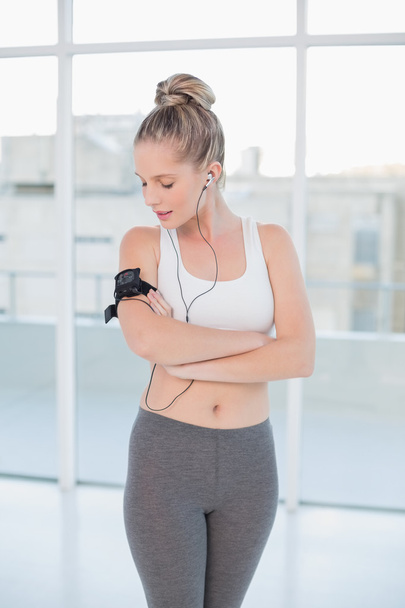 Relaxed sporty blonde wearing armband holding mp3 player - Fotografie, Obrázek