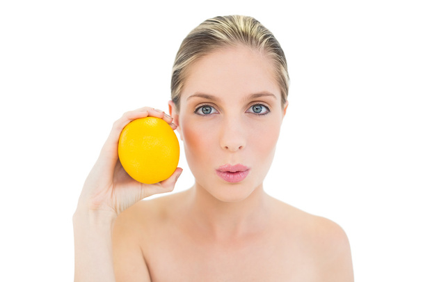 Attractive fresh blonde woman pouting and holding an orange - Foto, Bild
