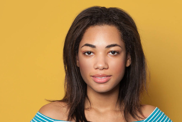 fröhliche junge schwarze Frau Gesicht Nahaufnahme Porträt auf gelbem Studiohintergrund - Foto, Bild