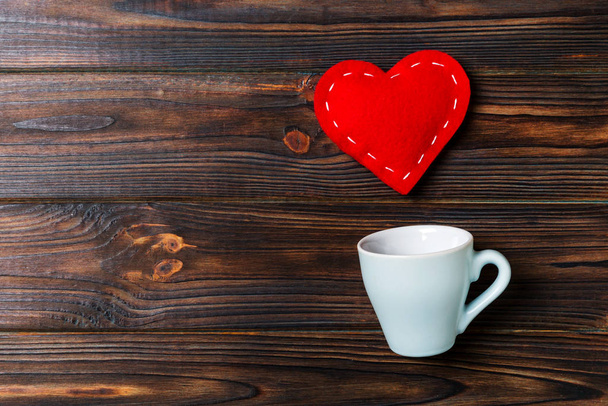 Top view of a cup and red hearts falling out from it on wooden background. Happy Valentine's Day concept - Fotó, kép