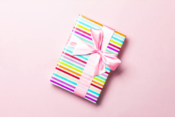 Κουτί δώρου με ροζ φιόγκο για την ημέρα των Χριστουγέννων ή της Πρωτοχρονιάς σε ροζ φόντο, πάνω άποψη με αντίγραφο χώρου - Φωτογραφία, εικόνα