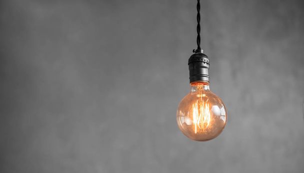 Lámpara retro Edison bombillas incandescentes sobre fondo de pared de yeso gris en loft. Concepto Estilo vintage. Copiar espacio
 - Foto, imagen