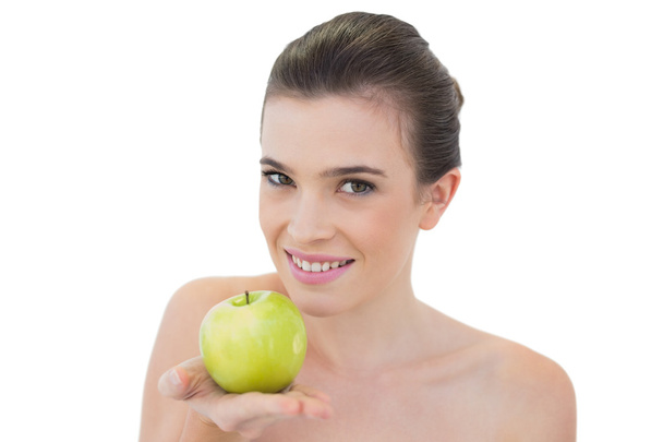 Happy model offering a green apple - Foto, afbeelding