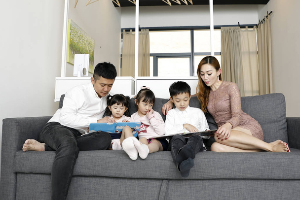 Rodzice Dziecko Rodzina ojciec matka córka syn siedzieć na kanapie czytać - Zdjęcie, obraz