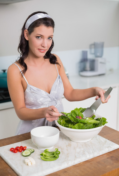 Smiling cute brunette mixing healthy salad - Photo, image