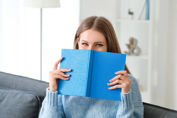 Beautiful young woman reading book at home - Foto, afbeelding
