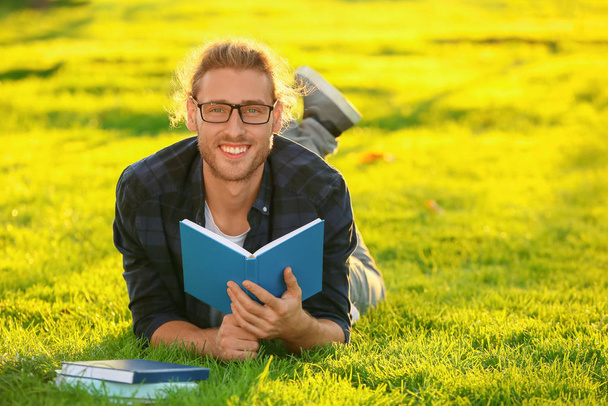 Красивий чоловік читає книгу на відкритому повітрі
 - Фото, зображення