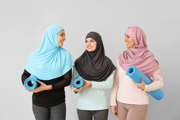 Deportivas musulmanas con colchonetas de yoga sobre fondo claro
 - Foto, Imagen