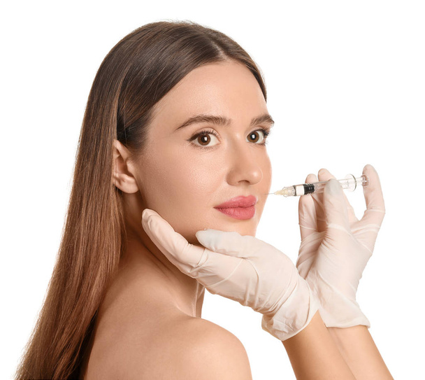 Mujer joven recibiendo inyección de relleno sobre fondo blanco
 - Foto, imagen