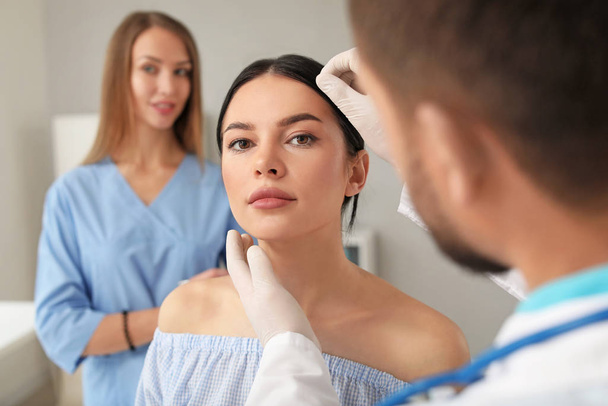 Schönheitschirurg untersucht Gesicht der jungen Frau vor Operation in Klinik - Foto, Bild