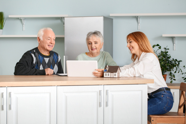 Agente inmobiliario femenino trabajando con pareja de personas mayores en interiores
 - Foto, imagen