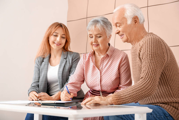 Agente inmobiliario femenino trabajando con pareja de personas mayores en interiores
 - Foto, imagen