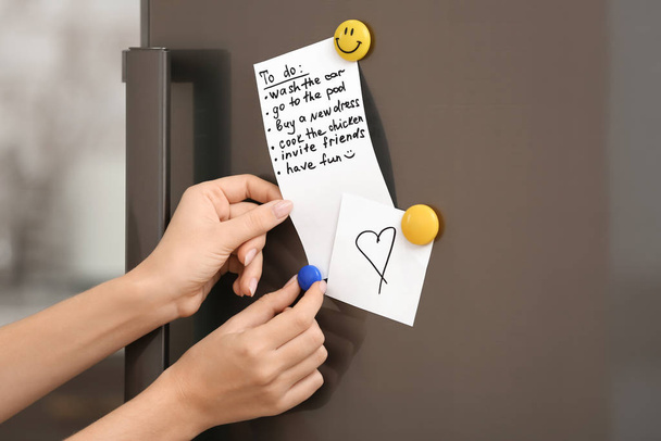 Woman checking to-do list on fridge in kitchen - Foto, immagini