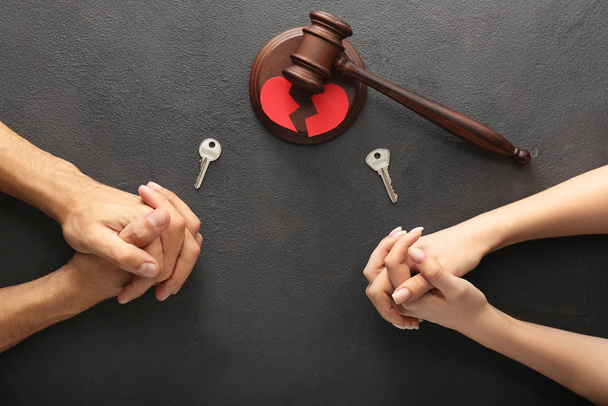 Mani di coppia con chiavi e martelletto del giudice su sfondo scuro. Concetto di divorzio
 - Foto, immagini