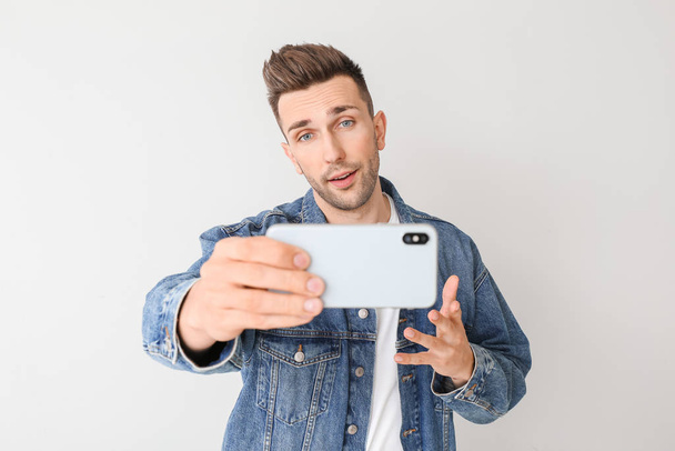 Handsome man taking selfie on light background - Фото, зображення