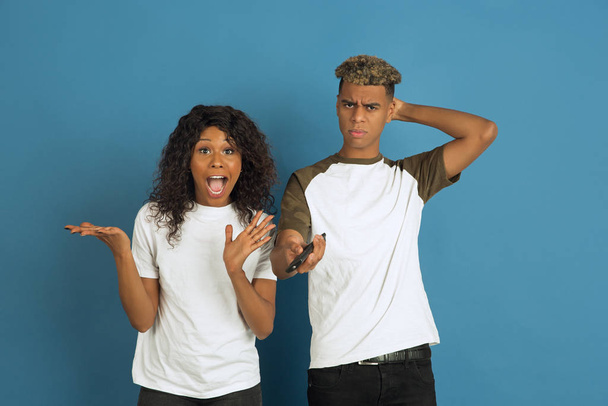 Young emotional african-american man and woman on blue background - Foto, afbeelding