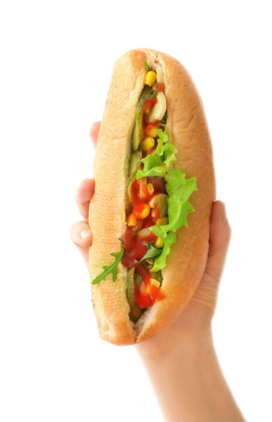 Female hand with tasty hot dog on light background - Foto, Bild