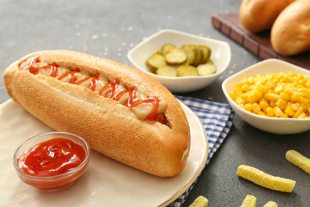 Bord met lekkere hotdog op tafel - Foto, afbeelding
