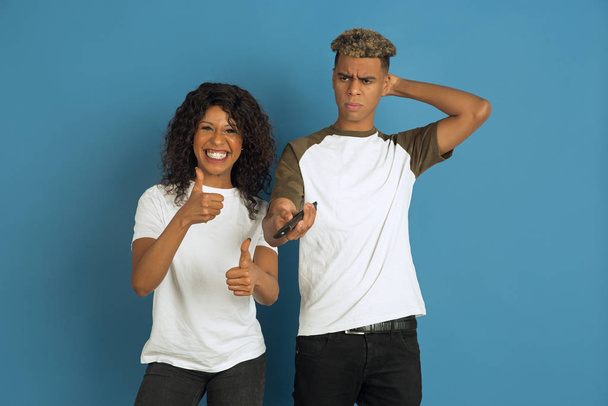 Молодой эмоциональный афро-американец мужчина и женщина на синем фоне
 - Фото, изображение