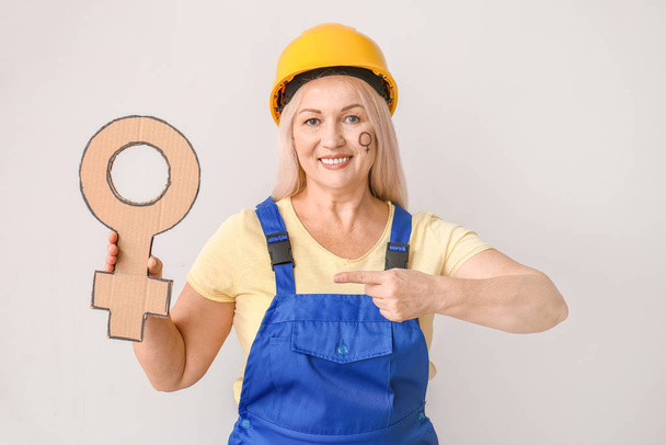 Female worker with symbol of woman on light background. Concept of feminism - Foto, afbeelding