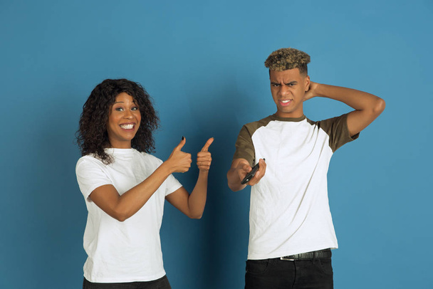 Young emotional african-american man and woman on blue background - Foto, Bild