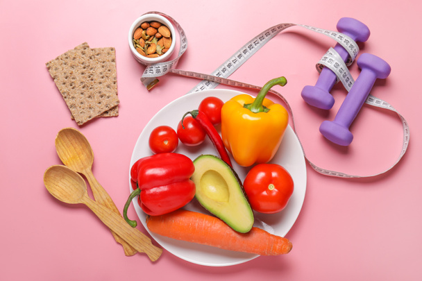 Different healthy food with measuring tape and dumbbells on color background. Diet concept - Photo, Image