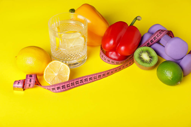 Diversi alimenti sani con nastro di misurazione e manubri su sfondo a colori. Concetto di dieta
 - Foto, immagini