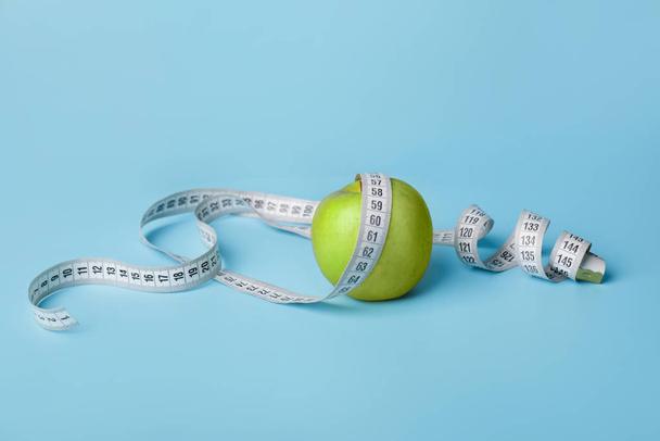 Apple and measuring tape on color background. Diet concept - Photo, Image