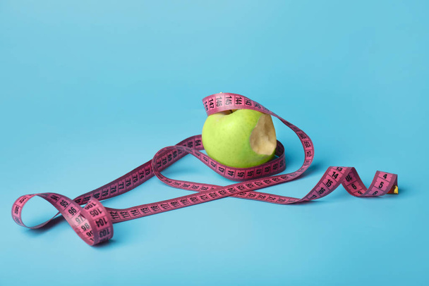 Кусанное яблоко и измерительная лента на цветном фоне. Концепция питания
 - Фото, изображение