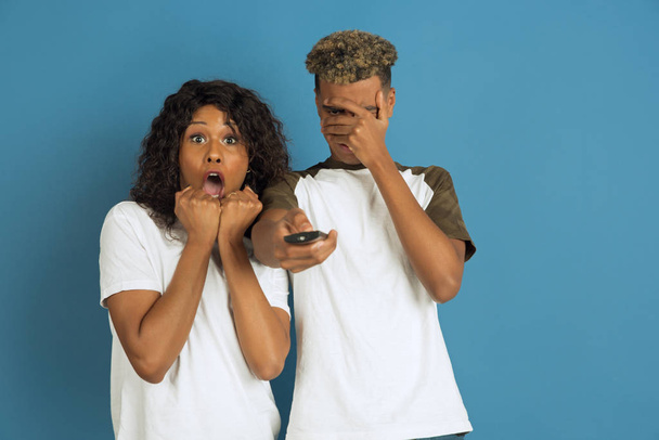 Young emotional african-american man and woman on blue background - Fotografie, Obrázek