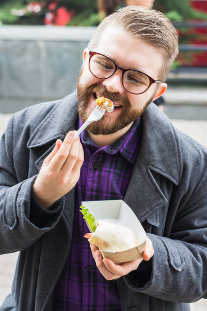 Close-up of man is holding falafel sandwich in paper bag. Healthy street food concept, oriental cuisine. - Photo, Image