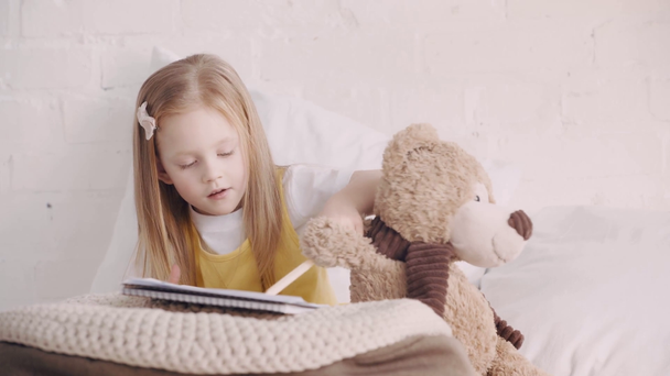 Enfant tenant ours en peluche tout en dessinant sur le lit
 - Séquence, vidéo