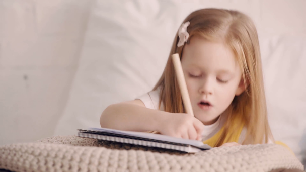 Child drawing while lying on bed - Záběry, video
