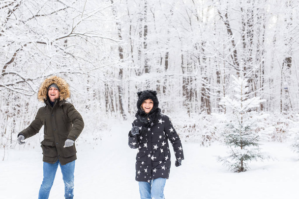 Fun, season and leisure concept - love couple plays winter wood on snow - Photo, Image