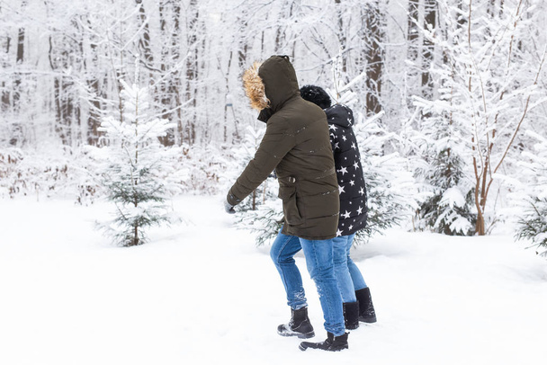 Una pareja joven y hermosa se está divirtiendo en el parque nevado, corriendo y tomándose de la mano. Concepto de San Valentín. Temporada de invierno. - Foto, Imagen