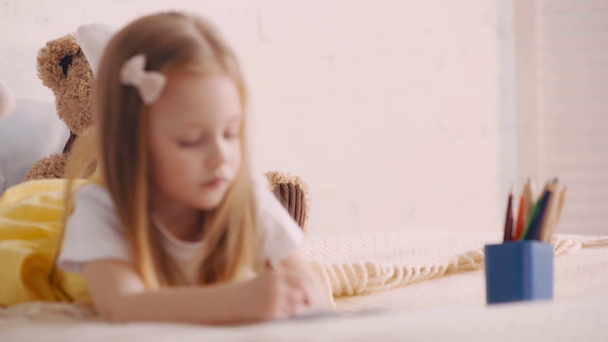Selectieve focus van teddybeer door kind tekening op bed - Video