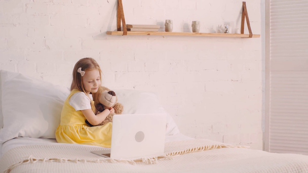 Oyuncak ayıyla gülümseyen çocuk dizüstü bilgisayarında film izliyor. - Video, Çekim